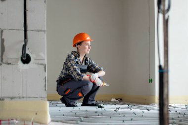 Yeraltı ısıtma sistemi kuran kadın işçinin portresi. Sıcak zemin ısıtma sistemi.