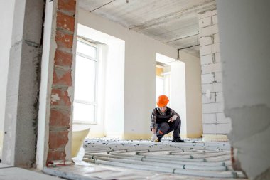 Kadın işçi yer altı ısıtma sistemi kuruyor. Sıcak zemin ısıtma sistemi.