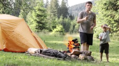 Mutlu baba ve oğul kamp alanında marşmelov kızartıyorlar. Yürüyüş, aileyle zaman geçirmek, aile hayatı, açık hava eğlencesi.