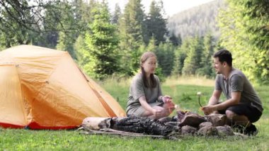 Bir adam ve bir kadın çadırın yakınındaki bir ateşte marşmelov kızartıyorlar. Kamp ateşinin yanında neşeli düşünceler. Kamp ailesi.
