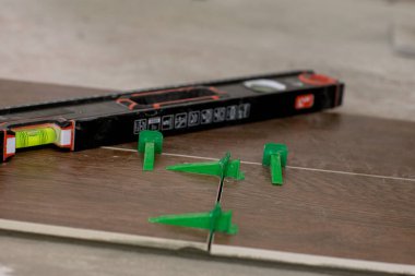 Döşeme düzleştirme sistemi, dört adet takozlu plastik yeşil şarjör. Yakın plan görünümü, seçici odak, bulanık arkaplan.