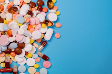 Mavi arka planda renkli haplar ve kapsüller. Asgari tıbbi konsept. Boşluğu kopyala.