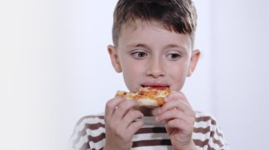 Küçük çocuk lezzetli bir şekilde salamlı pizza yiyor..