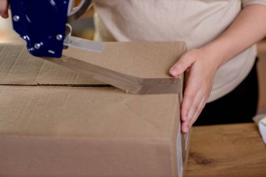Kadın ellerinin çevrimiçi görüntüsü küçük işletme sahibi satıcı girişimci paketleme paketleme posta kutusu teslimat paketi masanın üzerinde. Ticaret düşüş nakliye hizmeti konsepti