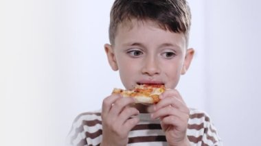 Küçük çocuk lezzetli bir şekilde salamlı pizza yiyor..