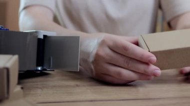 Kadın ellerinin çevrimiçi görüntüsü küçük işletme sahibi satıcı girişimci paketleme paketleme posta kutusu teslimat paketi masanın üzerinde. Ticaret düşüş nakliye hizmeti konsepti