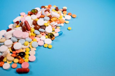 Mavi arka planda renkli haplar ve kapsüller. Asgari tıbbi konsept. Boşluğu kopyala.