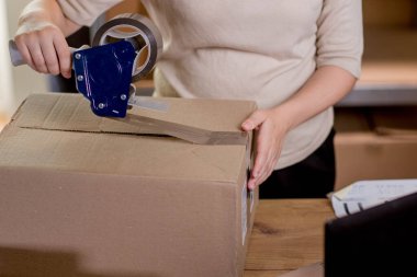 Kadın ellerinin çevrimiçi görüntüsü küçük işletme sahibi satıcı girişimci paketleme paketleme posta kutusu teslimat paketi masanın üzerinde. Ticaret düşüş nakliye hizmeti konsepti