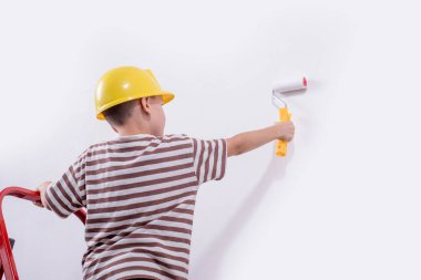 Boyalı silindirli şirin bir çocuk. Mutlu çocuk ebeveynlerin duvar boyamasına yardım eder. Aile için yeni bir ev