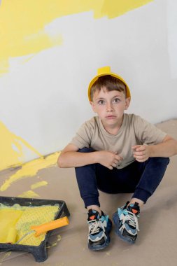 Ev tamiri. Boyalı silindirli şirin bir çocuk. Mutlu çocuk ebeveynlerin duvar boyamasına yardım eder. Yeni ev yenileme konsepti