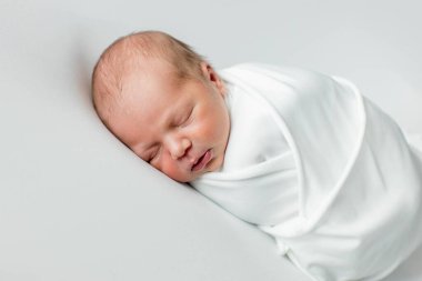 Beyaz arka planda uyuyan şirin yeni doğmuş bebeğe yakın çekim. Bakım, sevgi, mutluluk konsepti.