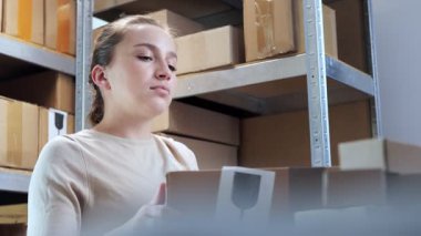 Bir kadın kutuları toplar, kutuyu rafa koyar. Malların teslimatı. Malların ambalajı depoda.