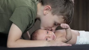 Ağabeyi yeni doğan kardeşini yanağından öpüyor. Mutlu bir aile. Mutlu yeni doğan bebek kardeşiyle.