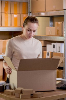 Gülümseyen bayan girişimci bant kutusunu kullanarak paketliyor. Kadın, ürün kutusunu müşteriye teslim etmek için hazırlıyor. Çevrimiçi iş, ekommerce ve dağıtım kavramı.