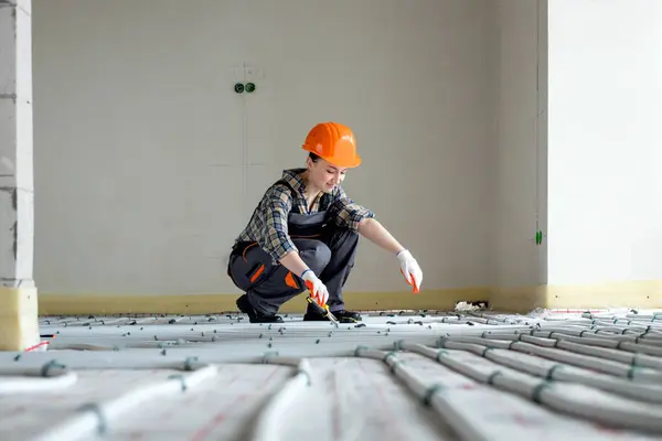 Woman worker is installing underfloor heating system. Warm floor heating system.