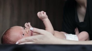 Genç, şefkatli bir anne yeni doğmuş bebeğini öpüyor ve onunla yakından konuşuyor. Anneliğin mutlu anları, çocuk ve annelik bağı, ebeveynlik, çocuk bakımı..