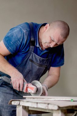 Açı öğütücüsüyle fayans kesen profesyonel bir işçi. İnşaat, yenileme, onarım...