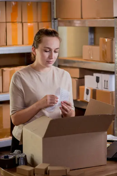 Woman checking goods in a box. Postal service and small business concept.