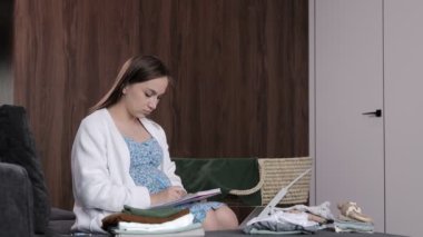 Hamile kadın doğum hastanesine gitmek için bebek kıyafetleri topluyor. Not alan kadın