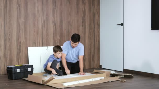 父と息子は新しいアパートの床に新しい家具を組み立て 経験とトレーニングの概念 — ストック動画