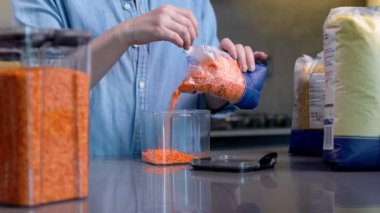 Kadın mutfaktaki depoyu düzenlemek için plastik kutu kullanıyor. Gıda ürünlerinin tasarımı ve sıralanması.