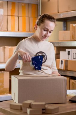 Gülümseyen bayan girişimci bant kutusunu kullanarak paketliyor. Kadın, ürün kutusunu müşteriye teslim etmek için hazırlıyor. Çevrimiçi iş, ekommerce ve dağıtım kavramı.