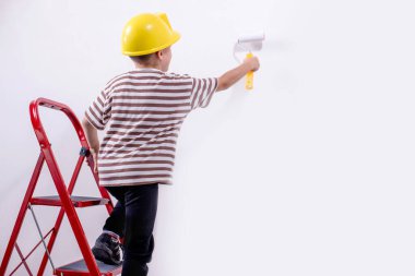 Boyalı silindirli şirin bir çocuk. Mutlu çocuk ebeveynlerin duvar boyamasına yardım eder. Ev yenilenmesi.