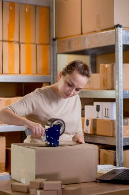 Gülümseyen bayan girişimci bant kutusunu kullanarak paketliyor. Kadın, ürün kutusunu müşteriye teslim etmek için hazırlıyor. Çevrimiçi iş, ekommerce ve dağıtım kavramı.
