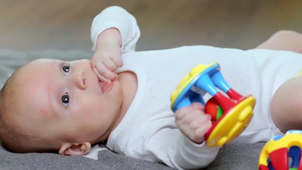 赤ん坊の少年は嘘をつき 彼の手に玩具を保持する — ストック動画