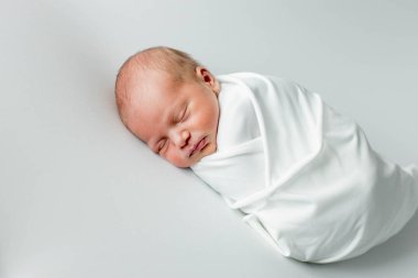 Beyaz arka planda uyuyan şirin yeni doğmuş bebeğe yakın çekim. Bakım, sevgi, mutluluk konsepti.