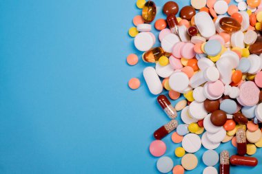 Mavi arka planda renkli haplar ve kapsüller. Asgari tıbbi konsept. Boşluğu kopyala.