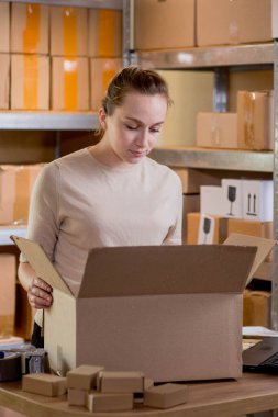 Kadın kutuda eşyaları kontrol ediyor. Posta hizmeti ve küçük işletme kavramı.