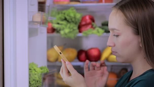 Женщина Добавляет Продукты Свой Список Время Покупки Продуктов Проверяя Холодильник — стоковое видео