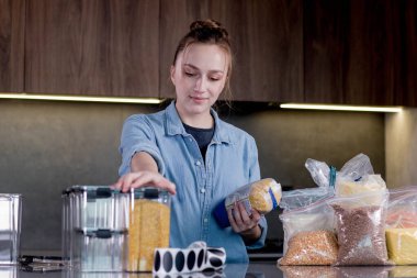 Yiyecek ürünlerinin tasarımı ve tasnif edilmesi. Kadın mutfaktaki yemekleri düzenlemek için konteynır kullanıyor. Organizasyonun modern mutfağın içinde yönetilmesi