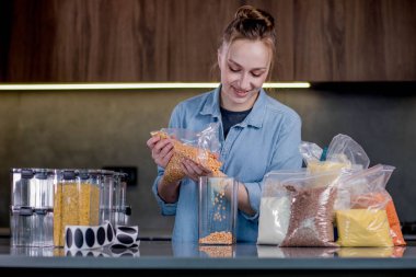 Yiyecek ürünlerinin tasarımı ve tasnif edilmesi. Kadın mutfaktaki yemekleri düzenlemek için konteynır kullanıyor. Organizasyonun modern mutfağın içinde yönetilmesi