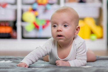 Küçük çocuk karnının üstünde yatarken bir oyuncakla oynuyor.