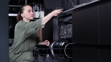 Kadın bulaşık makinesinden temiz bulaşıkları boşaltıyor.