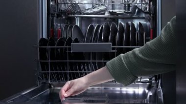 Bulaşık makinesine mavi deterjan koyan kadın.