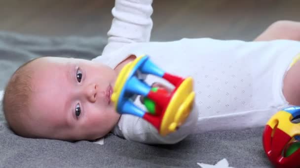 Bebé Niño Miente Sostiene Juguete Sus Manos — Vídeos de Stock