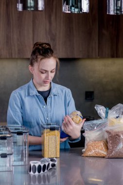 Konforlu ürün deposu için plastik kutularla poz veren mutlu kadın profesyonel uzay organizatörü. Organizasyonun modern bir mutfağın içinde yönetimi..