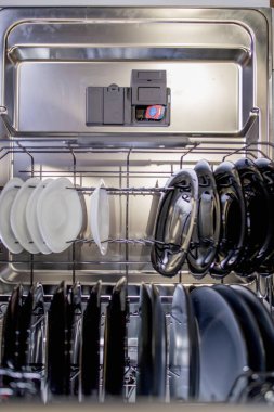 Bulaşık makinesinde yıkanmak için renkli bir kapsül. Bulaşık makinesinin üst tarafı bulaşık dolu..