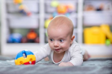 Bebek oyuncağa uzanıyor. Bebek gelişimi.