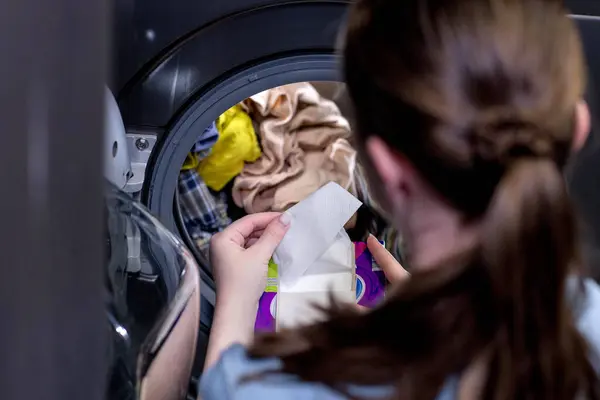 洗濯機の前に座っている女性汚れた服 着色された服を洗うためのナプキン ロイヤリティフリーのストック写真