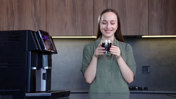 キッチンの近代的な機械の近くで新鮮な芳香族のコーヒーを楽しんでいる幸せな女性 — ストック動画