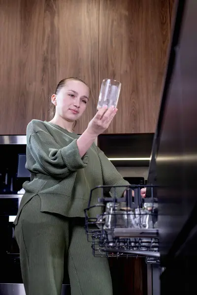 自宅で食器洗い機から清潔な料理をアンロードする女性 ストック画像