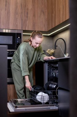 Kadın bulaşık makinesinden temiz bulaşıkları boşaltıyor..
