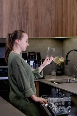 Kadın mutfaktaki bulaşık makinesinden bir bardak çıkardı.