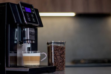 Mutfakta bir fincan cam latte ile modern kahve makinesi..