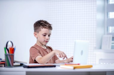 Uzaktan öğrenme çevrimiçi eğitim. Bir okul çocuğu evde dizüstü bilgisayar kullanarak ders çalışıyor. Ev uzaklığı öğrenimi.