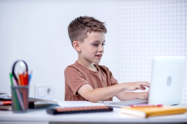 Uzaktan öğrenme çevrimiçi eğitim. Bir okul çocuğu evde dizüstü bilgisayar kullanarak ders çalışıyor. Ev uzaklığı öğrenimi.